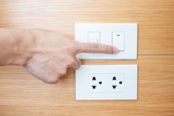 Closeup Male finger is turn on or off on light switch on white wall at home. Energy Saving, power, electrical and lifestyle concepts