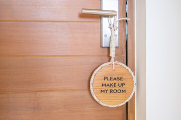 Closeup sign PLEASE MAKE UP MY ROOM hanging near wooden door at luxury hotel
