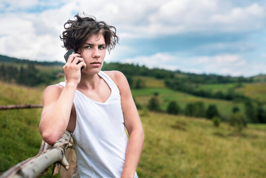 A Handsome Courageous Teenage Boy Talks On The Phone Outside The City Where He Is Resting In The Mountains, The Guy Misses His Girlfriend And Often Calls Her