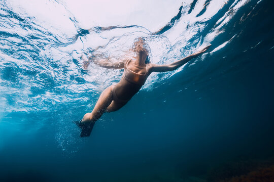 Sporty woman with fins swim in blue ocean