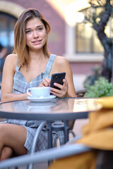 A woman uses a smartphone in a cafe on the street of the old city