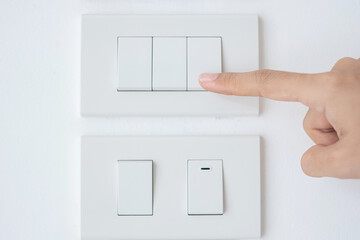 Closeup Male finger is turn on or off on light switch on white wall at home. Energy Saving, power,...