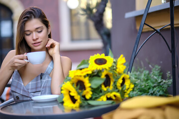 Young woman  drinking coffee in a cafe on the street of the old city