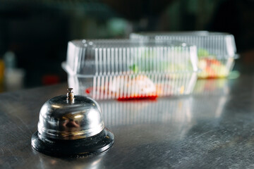 food delivery. distribution table in a restaurant with a metal bell. food in plastic containers....