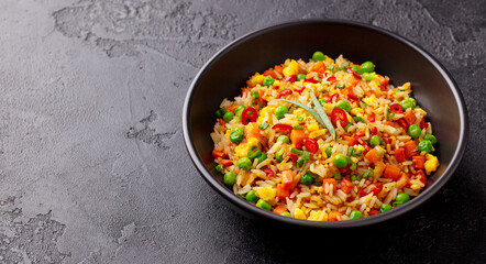 Asian fried rice with egg and vegetables. Stone background. Close up. Copy space.