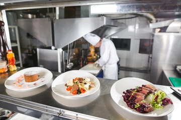 the distribution table in the kitchen of the restaurant. the chef prepares a meal on the background of the finished dishes.