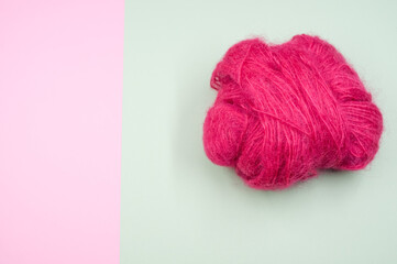 High angle shot of a ball of pink yarn on a blue and pink surface