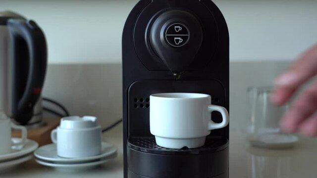 Man takes white cup of hot freshly cooked espresso coffee