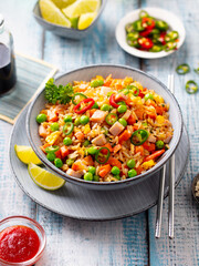 Asian fried rice with ham and vegetables. Blue wooden background. Close up.
