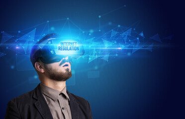 Businessman looking through Virtual Reality glasses with INTERNET REGULATION inscription, cyber security concept