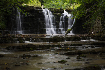 Hidden waterfall in a deep gorge with trickling white water. Forest of Bowland, Ribble Valley,...