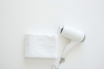 White Hair dryer and cotton towel on bed at luxury hotel or modern home with copy space for text