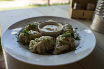 large dumplings with sour cream and herbs are on a plate
