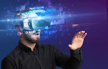 Businessman looking through Virtual Reality glasses with ENERGY inscription, innovative technology concept