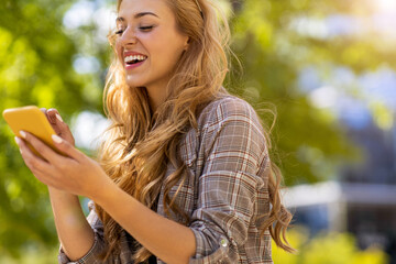 Happy young woman using smartphone in the city
