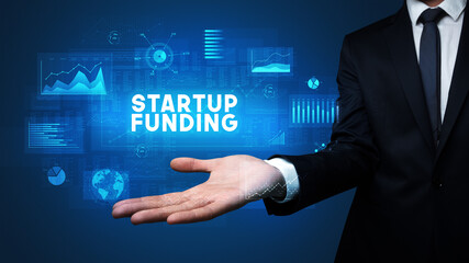 Hand of Businessman holding STARTUP FUNDING inscription, business success concept