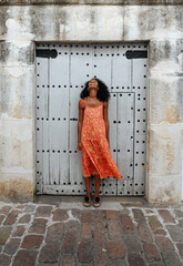 Young ethnic woman standing near old door