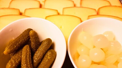 Cheese tray with small onion bowls and pickles close-up