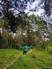 a child ride the homemade bungee in a pine forest on a Sunny day