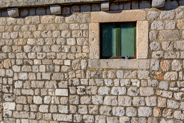 Colorful fortress street walk scene, ancient stone wall, green window and single pigeon. Winter view of Mediterranean old city of Dubrovnik, famous European travel and historic destination, Croatia