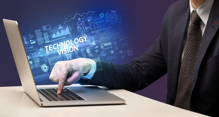 Businessman working on laptop with TECHNOLOGY VISION inscription, cyber technology concept