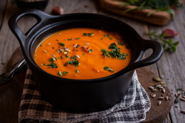 Hot pumpkin soup in cooking pot on dark background