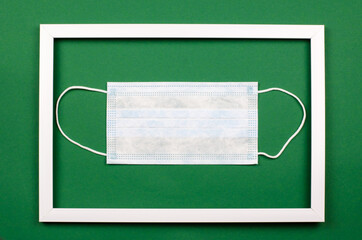 Protective medical mask in a white frame on a green background. Surgical mask for operations.