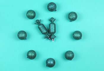 A clock from New Year's toys on a mint background. The time is 23:55. Christmas card