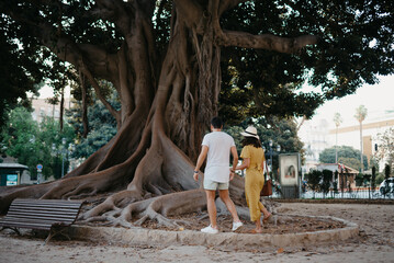 Woman with her boyfriend go to an old Valencian Ficus Macrophylla tree in Spain