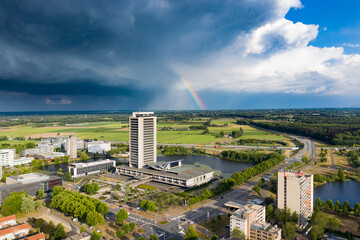 Den Bosch, 8 jun 2020 - The high rise tower skyscraper called provinciehuis with dark clouds and a rainbow in Den Bosch, Brabant, Netherlands.
