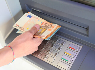 hand withdrawing money from the ATM with European banknotes