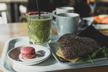 Rye bread sandwich, green smoothie, macaron and coffee breakfast or brunch