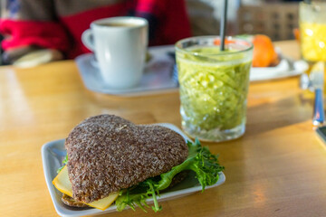 Rye bread sandwich with salad and cheese, green smoothie and coffee for breakfast