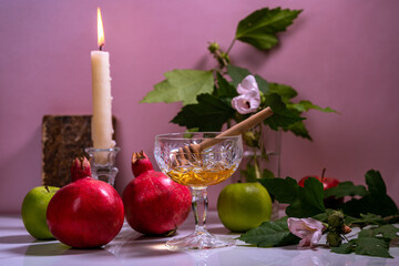 Jar of honey, candle, apples, old book and pomegranates on the table for the holiday of Rosh Hashanah