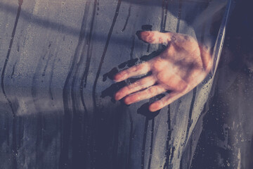 Handprint, palm on a transparent film with water drops. Dark and terrible trace from the palm,...