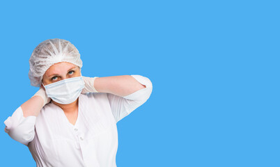 A tired nurse in a white coat with a hat and gloves. On a blue background. Close-up. Place for inscription