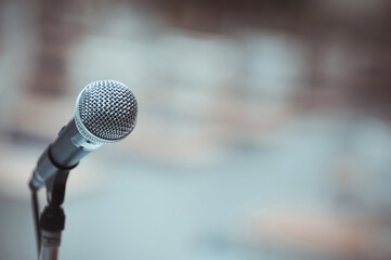 Microphone on abstract blurred of speech in seminar room or speaking conference hall light.
