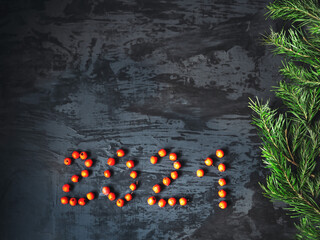 Dark background with a New Year theme and the inscription 2021 of rowan berries and spruce branches