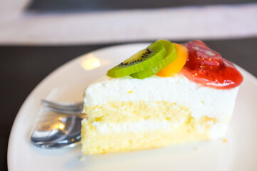 Delicious white creamy cake with berries and kiwi fruit on table