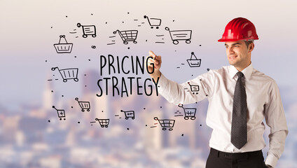 Handsome businessman with helmet drawing PRICING STRATEGY inscription, contruction sale concept