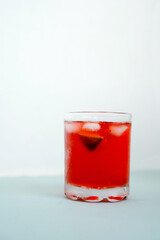 Red sparkling drink in the glass with ice and lime