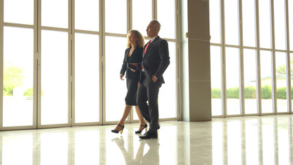 Businessman and businesswoman discussing work while walking