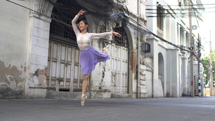 Fototapeta na wymiar Young beautiful ballerina dancing along the street