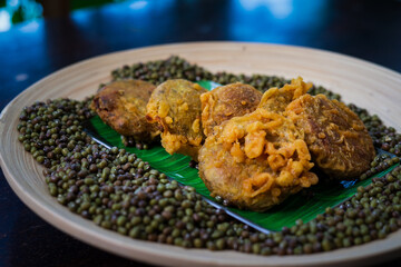 Kuih kasturi, a malaysian snack food made from green beans. Fried and served on a wooden plate.