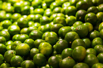 Background of tangerine fruits. Selective focus. Fresh Juicy Green Mandarin Heap on Market Stall