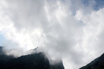 
The peaks of the High Tatras with white clouds. Mountains in the clouds. High Tatras Mountains in Slovakia