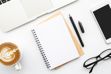 Blank notebook with smartphone are on top of white office desk table with cup of coffee and supplies. Top view with copy space, flat lay.