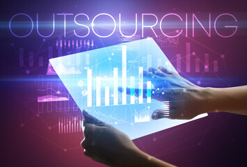 Hand holding futuristic tablet with OUTSOURCING inscription above, modern business concept