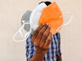 South Indian man showing three KN-95 face masks in white,grey and orange color. Isolated on white background.