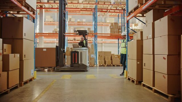 Retail Warehouse full of Shelves with Goods in Cardboard Boxes, Workers Scan and Sort Packages, Move Inventory with Pallet Trucks and Forklifts. Product Delivery Logistics Center. Dolly Shot